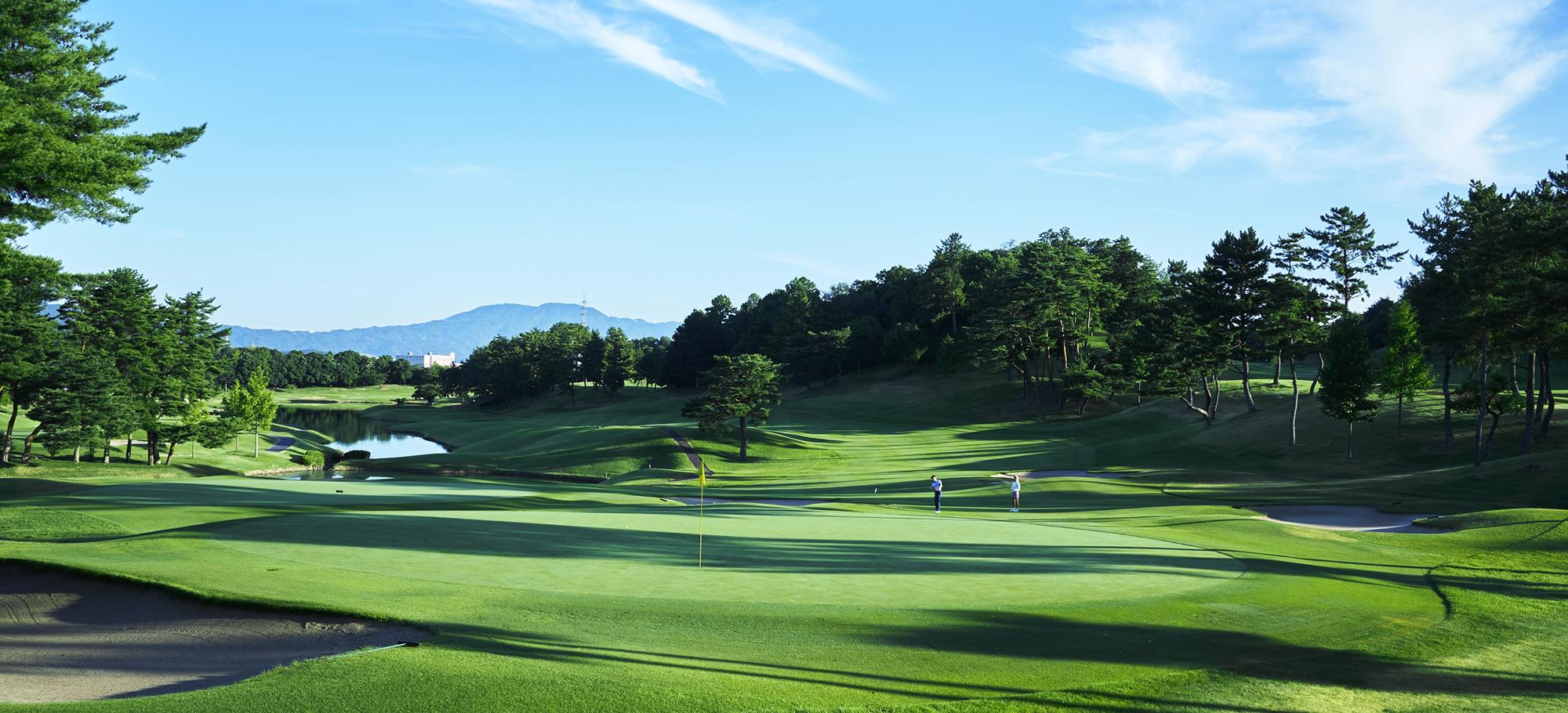 A green at Seta Golf Course North, with a pond to the left and hills behind